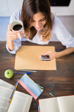 Woman checking the phone wile studying