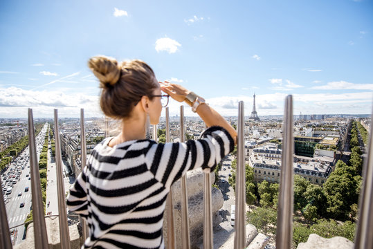 Young woman tourist enjoying great cityscape view on Paris during the sunny weather in France. Image focused on the background woman is out of focus