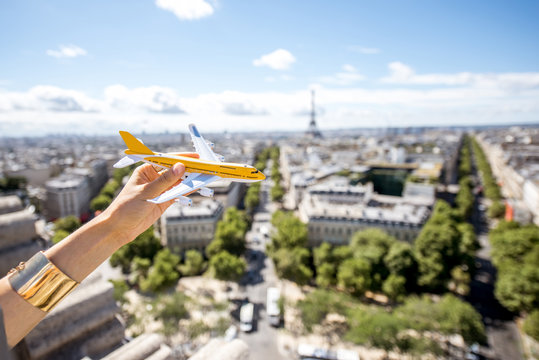 Holding a toy airplane on the Paris cityscape background. Air connection and tourism concept in the capital of France