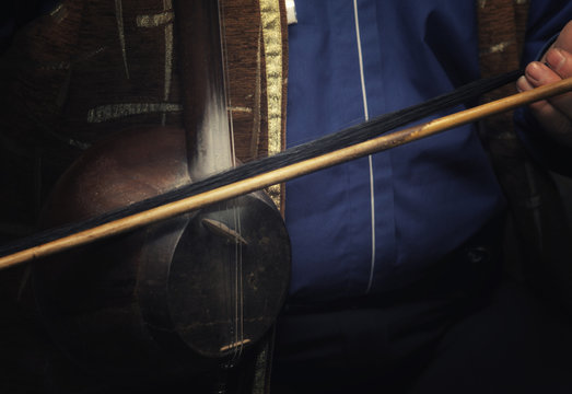 the musician plays on a traditional Middle Eastern and Asian stringed musical instrument