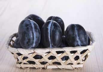 Ripe plums in a small basket