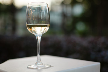 A glass of wine on a white table on a green background