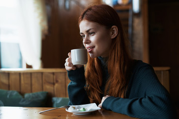 Beautiful young woman having breakfast in a cafe drinking coffee