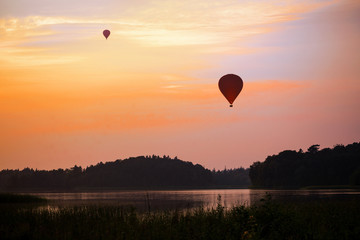 hot air balloon over a lake and forest landscape in the evening sky at sunset,  leisure activity and beautiful nature experience