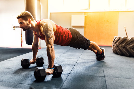 Handsome Muscular Man Doing Pushup Exercise With Dumbbell In A Crossfit Workout