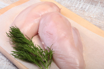 Fototapeta premium Raw chicken breast fillets and garlic ready for cooking on wooden board