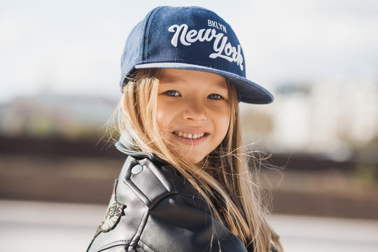 Portrait of a blond little girl in a dark blue hat smiling