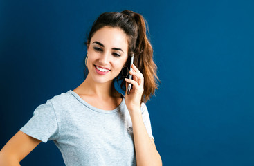 Young woman talking on the phone on a dark blue background