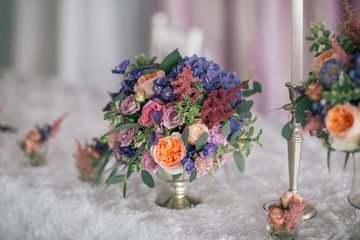 flower bouquet in vade with candles on the white decorated table