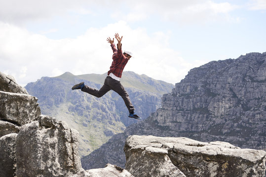 A male hiker jumps with joy in a scenic mountainous terrain