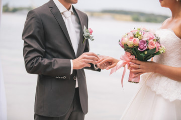 Newlyweds exchange rings, groom puts the ring on the bride's hand.
