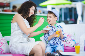 Boy and mother or happy family having healthy breakfast in resort cafe outdoor