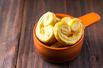 Sweet pretzels made of puff pastry in a bowl on a wooden table