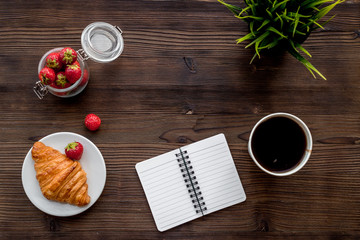 Light summer lunch. Coffee, strawberry, croissant on wooden background top view