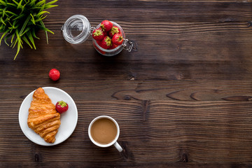 Light summer lunch. Coffee, strawberry, croissant on wooden background top view copyspace