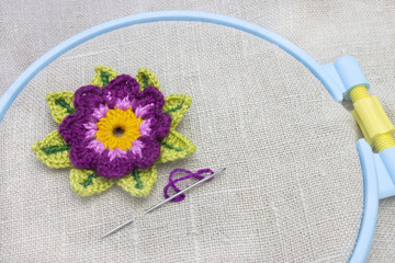 The beginning of needlework on an embroidery hoop. Needle and lothus flower on the linen cloth.