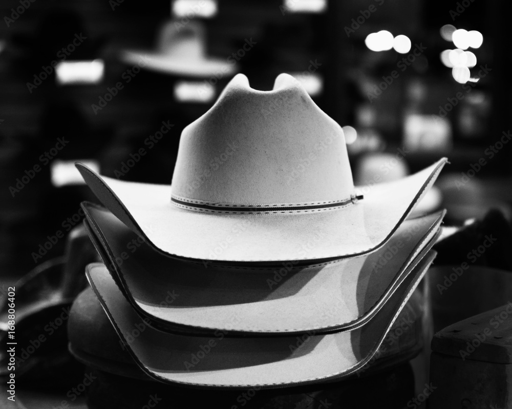 Wall mural Black and white felt cowboy hats in western retail store, under lights.  