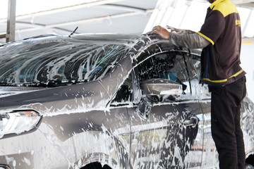 Worker washing car at the car wash shop