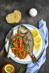 Baked dorado or sea bream with spring vegetables .Top view.