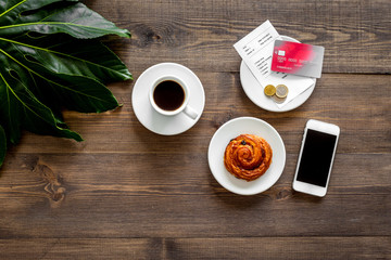 Restaurant bill and bank card near cup of coffee on dark wooden table top view copyspace