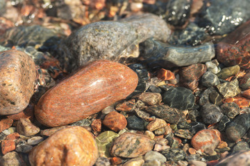 Wet round stones covered with clear sea water