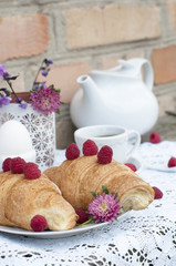 Breakfast with cup of coffee. A dessert with croissants and berries of raspberry on white a lace tablecloth