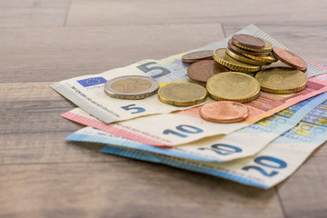 Euro banknotes and cents on a wooden table