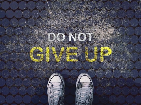 Do not give up word and sneakers shoes on grunge road , business concept