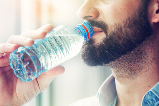 bearded man drinking bottle of water