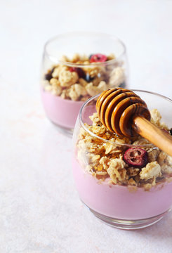 Two glasses of fruit yoghurt with granola and honey