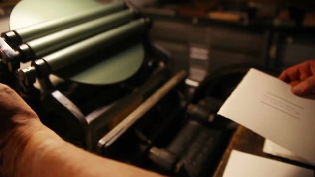 A printer works on a set of cards on an antique press