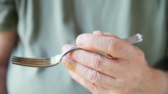 An older man holds a fork well despite a mild disability