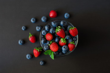top view of Strawberry and blueberry in glass bowl on round plate mat, selective focus of mix fresh fruit