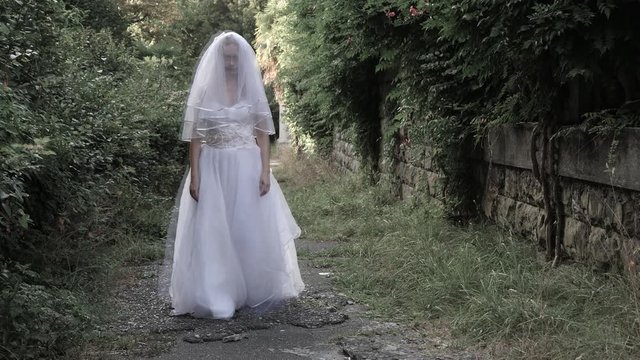 The ghost of the bride wanders through the ruins of the old castle. Bride of the Zombie. 4 k. Slow-motion shooting