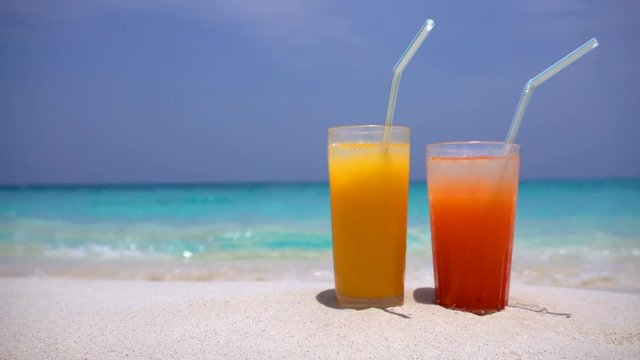 Two Cocktails in glass on white sandy beach with sea background. Travel destinations, nobody