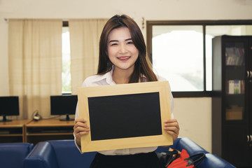 Portrait of a young woman holding a chalkboard.