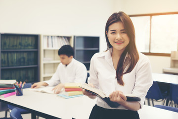 Young Asian students at the library reading a book. Education concept.