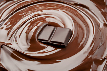 Melted pieces of chocolate bar in splash. Top view.