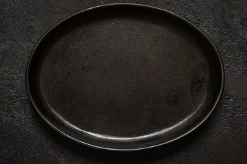 Empty rustic black cast iron plate On Dark concrete background. Top view with copy space
