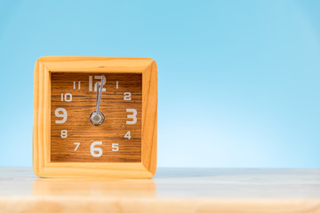 wood alarm clock on the table and blue background