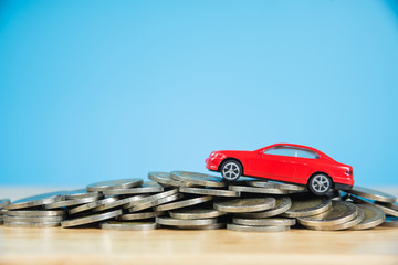 red miniature car model on stack of coins