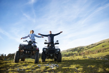 Beautiful couple is watching the sunset from the mountain sitting on quadbike