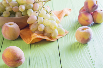 Fresh ripe peaches and grape on wooden background.