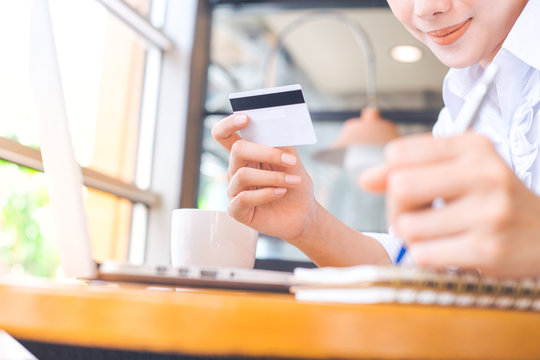 A woman's hand holds a credit card and uses  a  laptop computer to shop online.