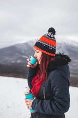 Fototapeta na wymiar Woman hold thermos with hot drink at winter. Mountain panorama in snow at background