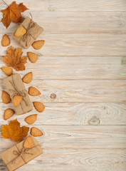 Flat lay frame of yellow leaves, cookies in the form of leaves, hazelnuts and gift boxes on a light wooden background.