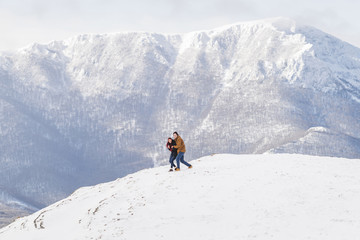 Naklejka na ściany i meble Loving couple in mountains on the background of snow-capped peaks