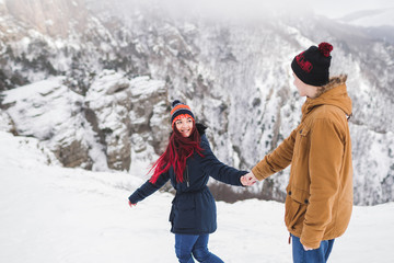 Couple in love walking in winter mountains. Beautiful view with snow, rocks and fog