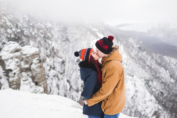 Fototapeta na wymiar Couple in love walking in winter mountains. Beautiful view with snow, rocks and fog