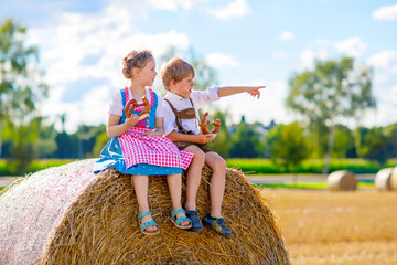 Two kids, boy and girl in traditional Bavarian costumes in wheat field